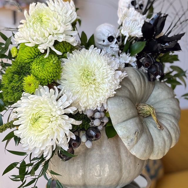 Ghostly Garden pumpkin centerpiece with white and green mums, ruscus, berries, and textured greenery