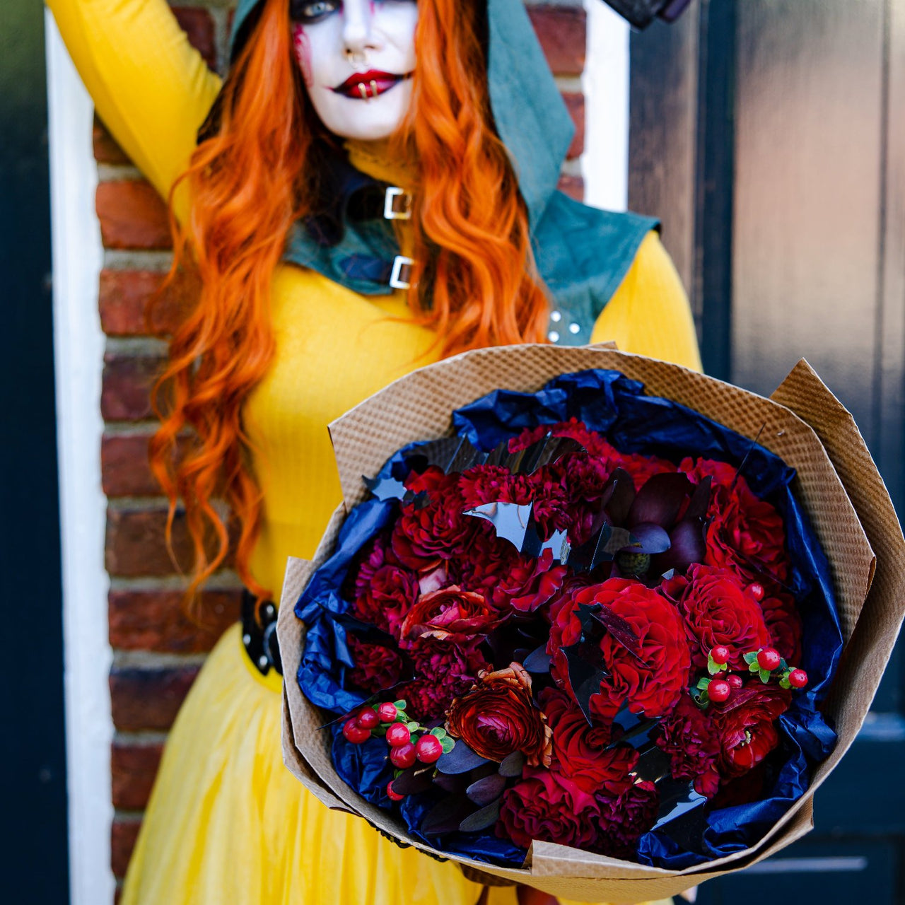 Halloween character is holding  deep red bouquet with bats.