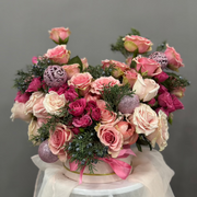 Holiday pink roses arrangement in a pink hat box with ornaments.