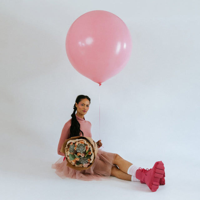 Bouquet of peach and pink flowers in the arms of a girl with a balloon
