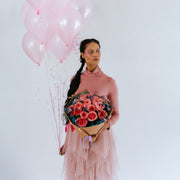 Pink flower bouquet  in the hands of a girl with balloons