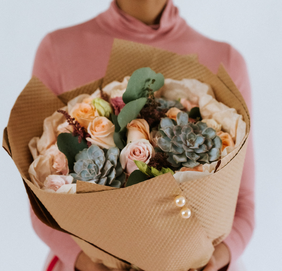 Bouquet of peach and pink flowers in the arms of a girl