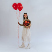 Bouquet of roses, carnations, and tulips in the hands of a girl in beige with balloons