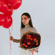 Bouquet of roses and tulips in the arms of a girl with balloons