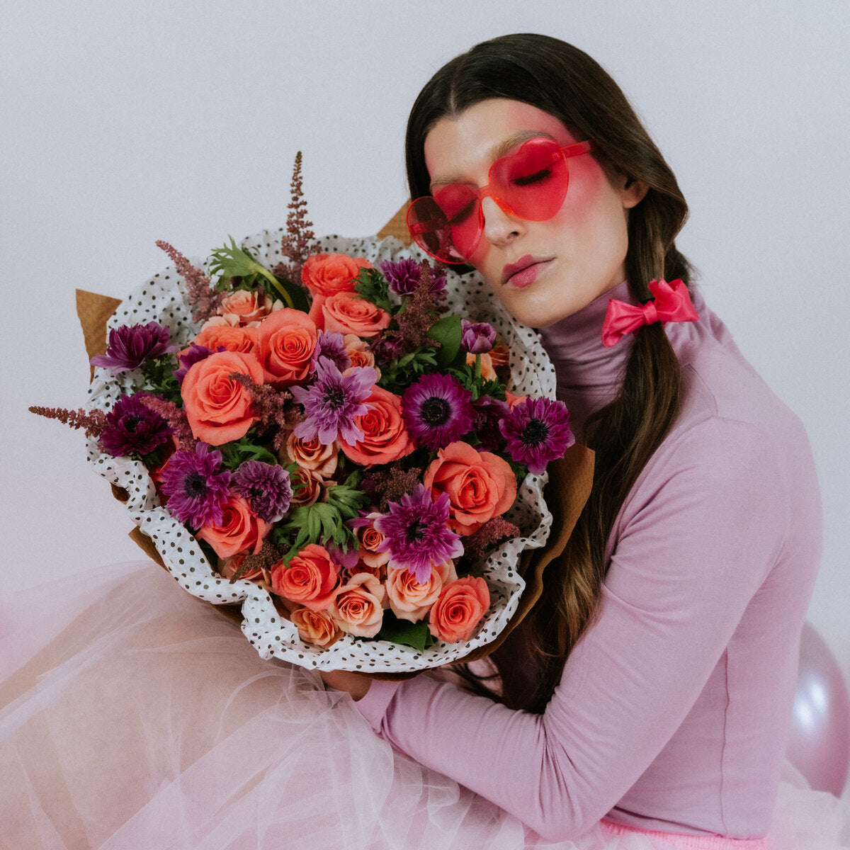 Bouquet of coral and pink flowers in the arms of a girl with glasses