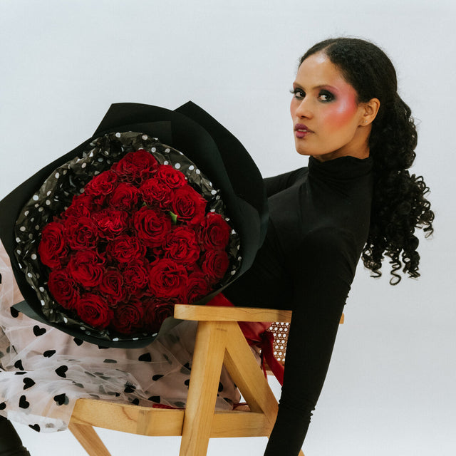 The girl is in black with a red bouquet of roses