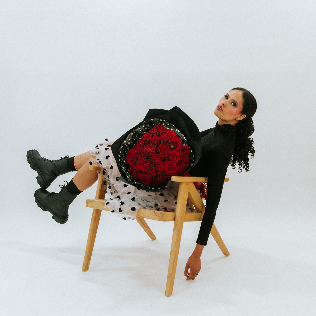 Red bouquet of roses in black wrapping paper in a girl's arms