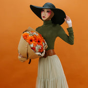 Bouquet of orange flowers in a girl’s hand in a black hat