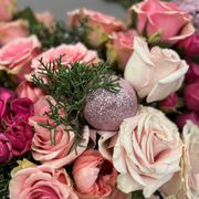 Close view of pink roses and holiday ornaments.