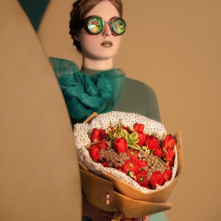 Red roses, tulips bouquet with succulent, held by a woman.