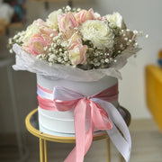 Soft romantic bouquet with pink tulips, ranunculus, white baby's breath, and cream tones.