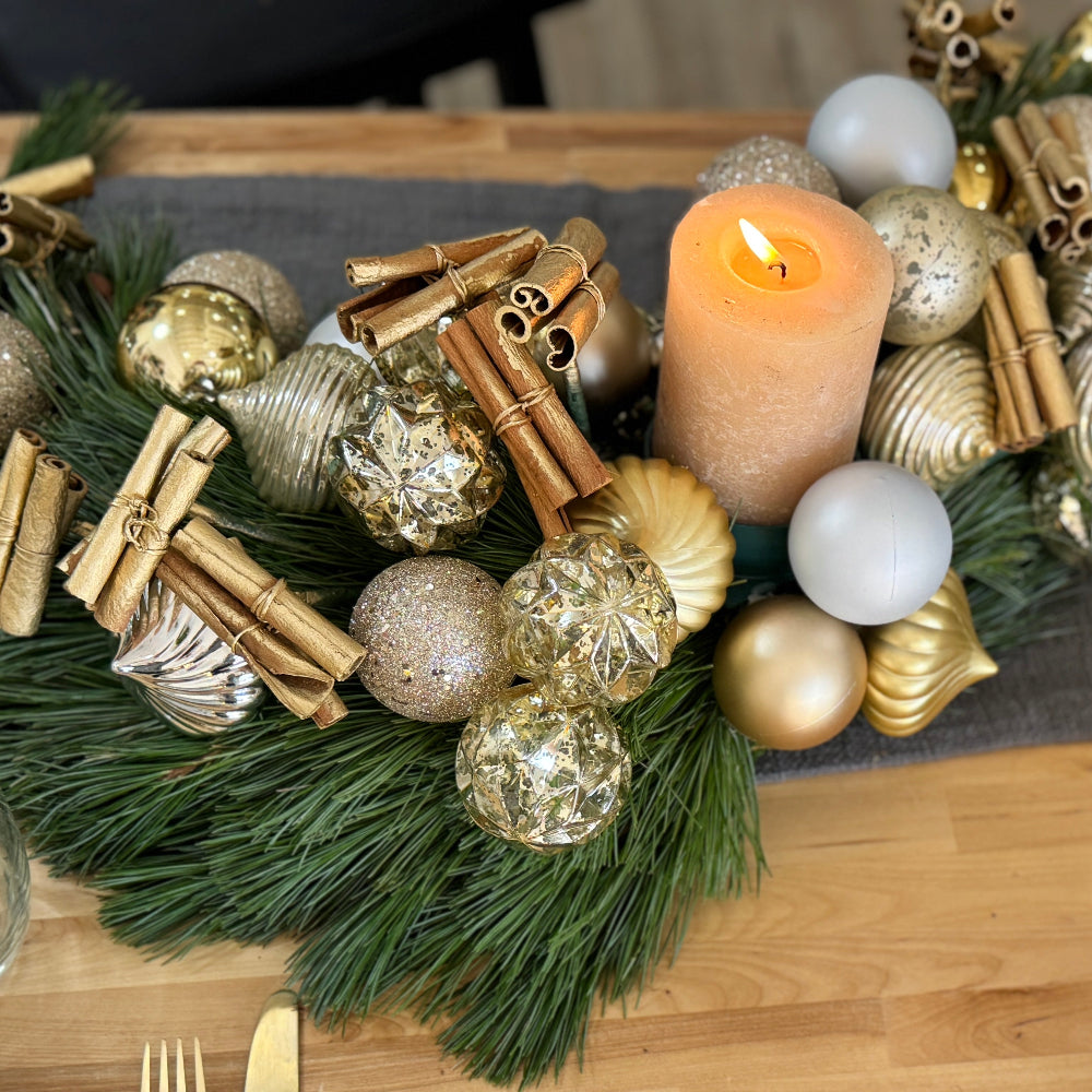 S-shaped holiday centerpiece made of fresh pine with gold and matte silver ornaments and space for a candle