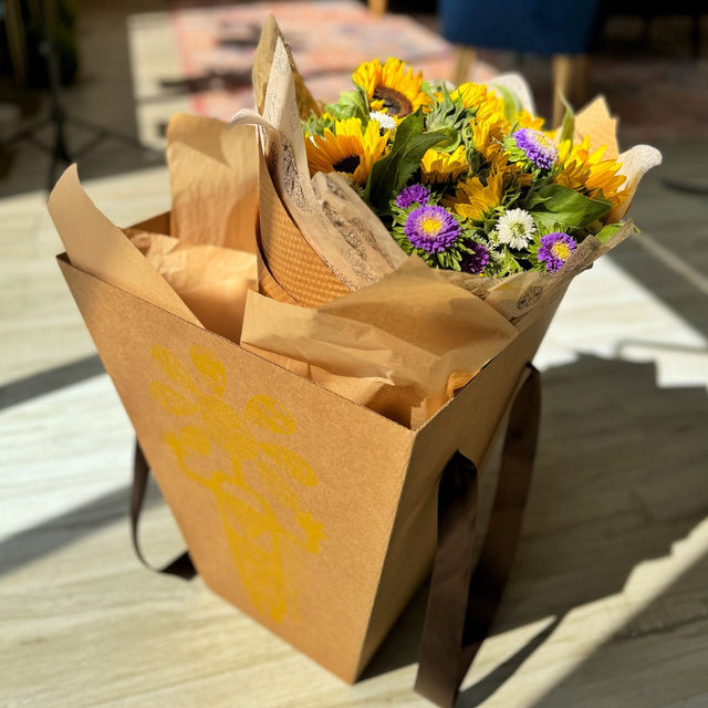 Bouquet in a delivery box with eco-friendly tissue paper and ribbon handles, ready for a special delivery.