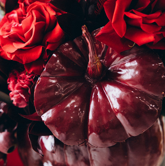Unique fall flower arrangement with red roses, rich seasonal textures, and a monochromatic red design.