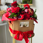 Romantic red flower arrangement in a soft pink clay vase, featuring premium roses, anemones, and seasonal botanical accents. 