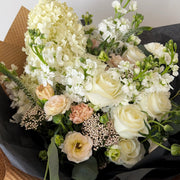 White and cream flowers, wrapped in black tissue and kraft paper