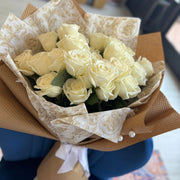 Classic bouquet of pure white roses, beautifully wrapped in kraft paper with delicate white ribbon and bead accents.