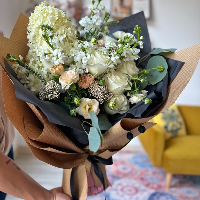 Gorgeous white and pastel colors flowers in black tissue and kraft paper