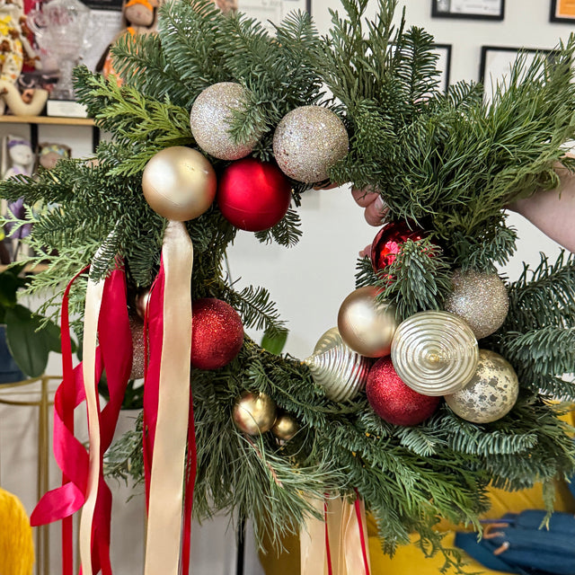 Decorative Christmas wreath with ornaments and ribbons on a chair