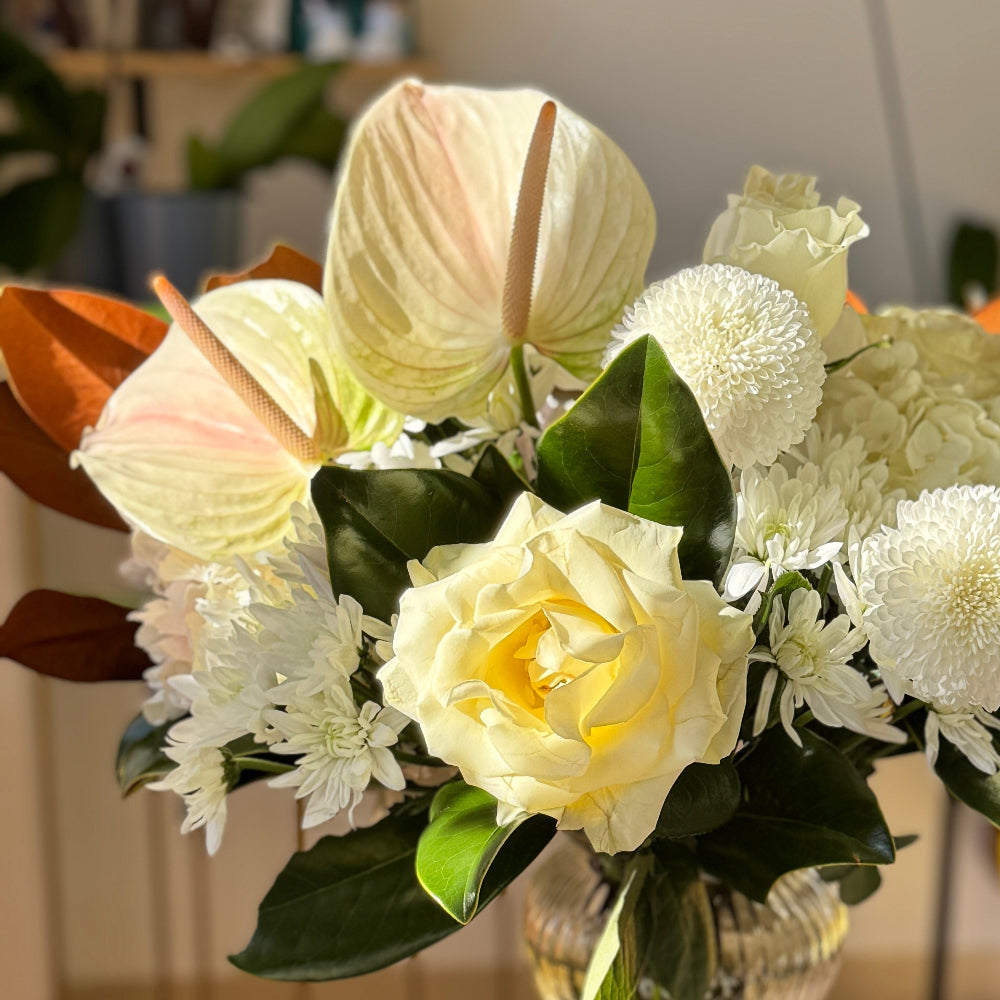 Floral arrangement in a clear vase on a small round table with a blurred indoor background