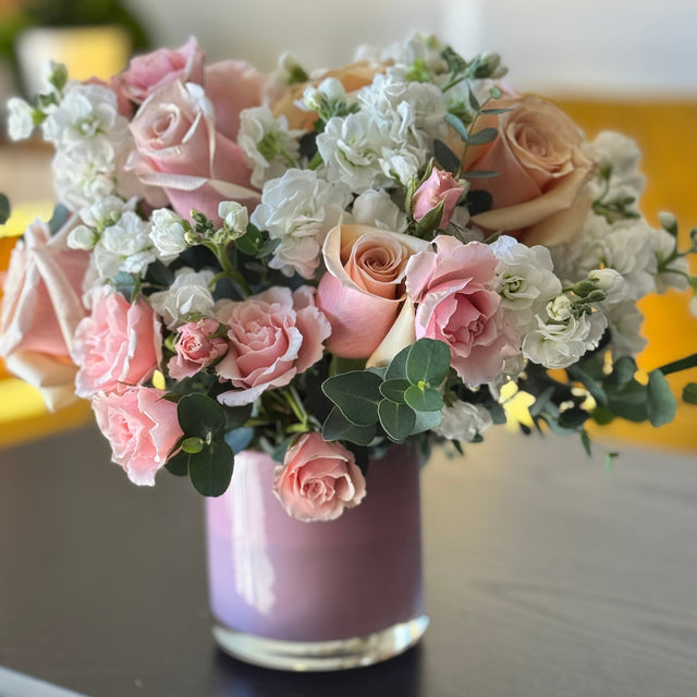 Pink Muse floral arrangement with light pink roses in a soft pink glass vase