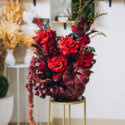 Modern autumn floral arrangement featuring vibrant red flowers in a beautifully painted pumpkin.