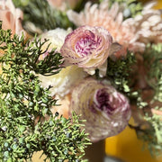 Close-up of a bouquet in the vase with pink flowers and greenery