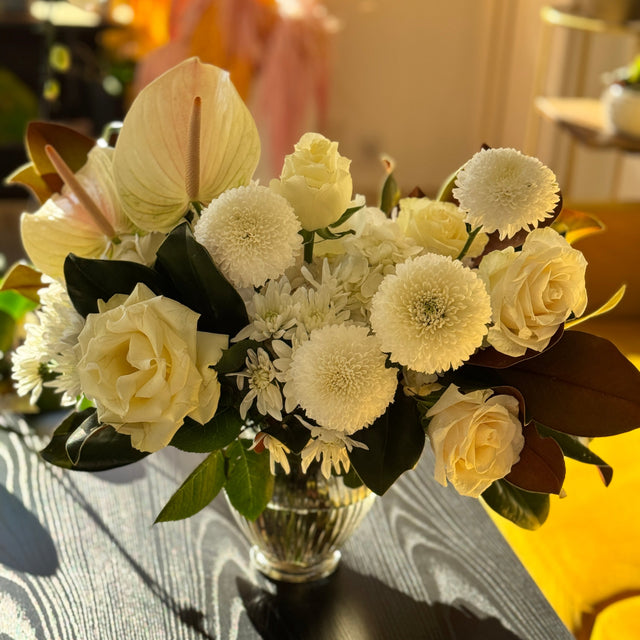 Winter Grace centerpiece in soft natural light, highlighting lush white blooms and rich green magnolia foliage.