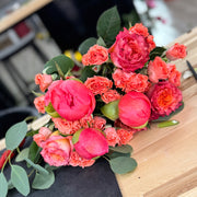 Coral Romance Bouquet with lush coral peonies, roses, and spray roses in soft romantic tones.