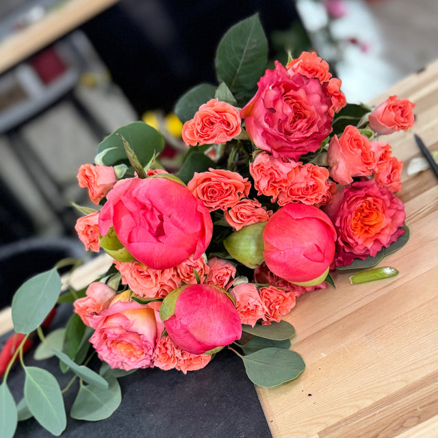 Coral Romance Bouquet with lush coral peonies, roses, and spray roses in soft romantic tones.