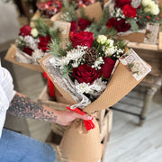 Person holding a bouquet of red and white flowers with more bouquets in the background.