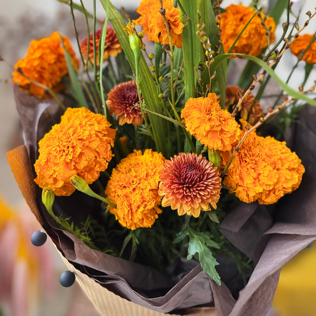 Bouquet of orange and brown flowers with green leaves on a blurred background