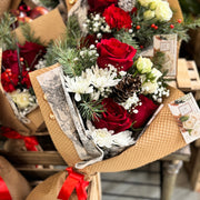 Bouquet of red and white flowers in a brown paper wrap with decorative elements.