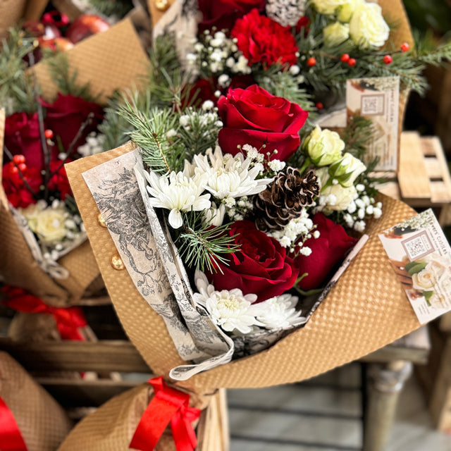 Bouquet of red and white flowers in a brown paper wrap with decorative elements.