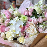 Close-up of luxury bouquet with pink and white roses and white cymbidium orchids.