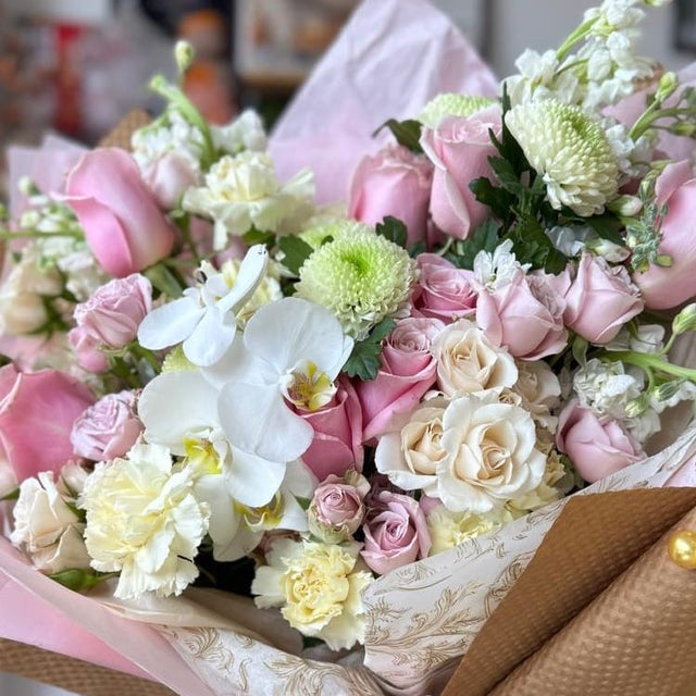 Close-up of luxury bouquet with pink and white roses and white cymbidium orchids.