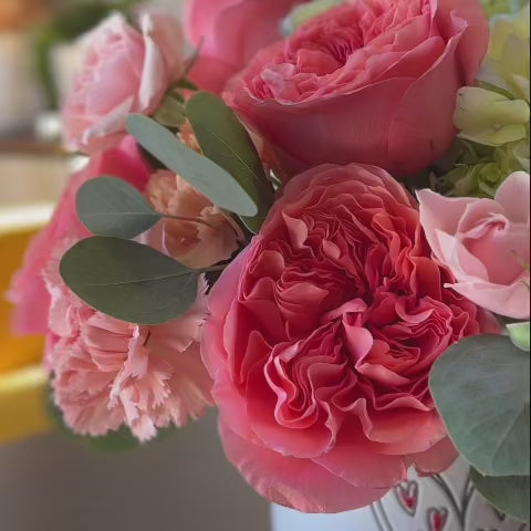 Video of a Valentine’s Day floral arrangement with roses and ranunculus in a heart-themed vase