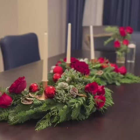 S-shaped evergreen centerpiece styled for an elegant holiday dining table