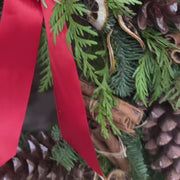 Holiday wreath with pinecones, lemon slices, cinnamon sticks, and a red bow.