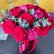 Bouquet of red and pink flowers with greenery on a dark surface