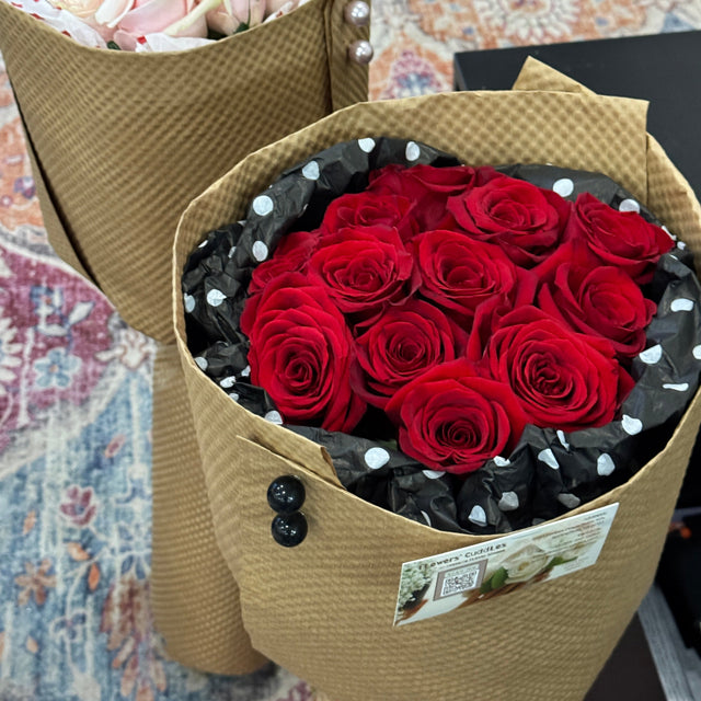Bouquet of red roses in a polka dot paper wrap on a patterned surface