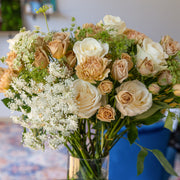 Champagne Dreams bouquet featuring cappuccino roses, white roses, cream carnations and Queen Anne's lace arranged in a vase without wrapping, showcasing the natural beauty of the flowers.