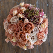 Top view of an arrangement in a hat box featuring cream roses, terracotta hydrangeas, and light pink lisianthus. The arrangement showcases a harmonious blend of earthy tones for an elegant and sophisticated display.