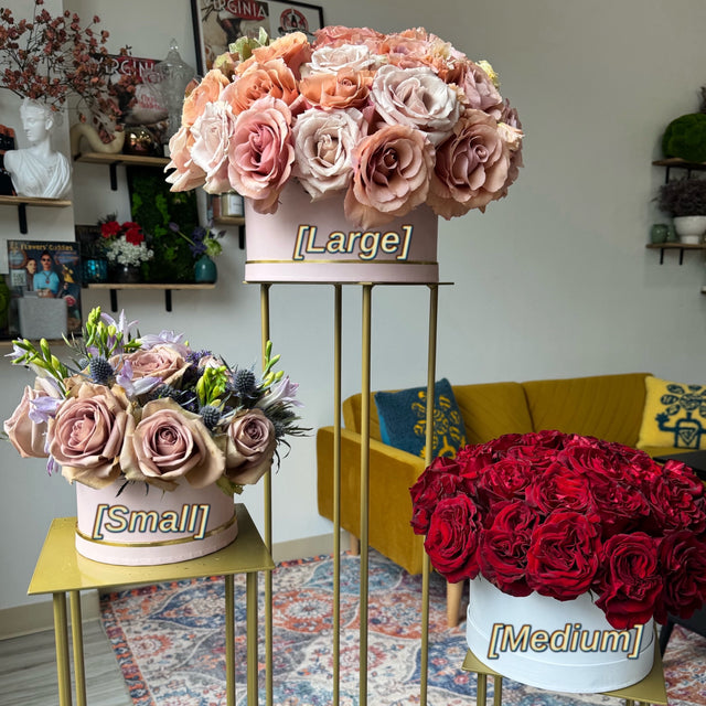 Three different sizes of hat boxes displayed on stands, each labeled with 'Small,' 'Medium,' and 'Large.' The boxes are elegantly arranged to showcase the variations in size.