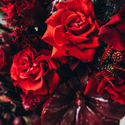 Close-up of luxurious red roses and deep burgundy blooms in a unique Thanksgiving centerpiece.