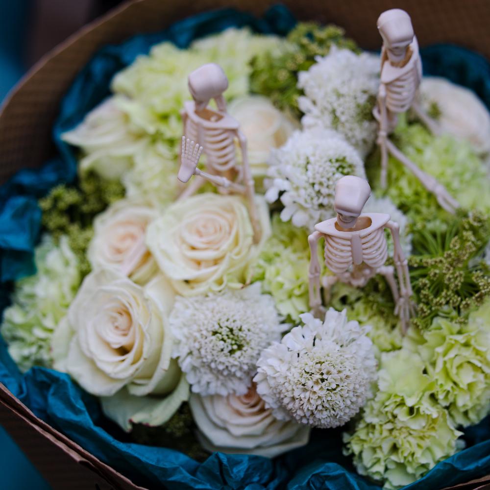 Close up of the Halloween fresh flowers bouquet of white and green flowers with skeletons.