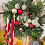 Decorative Christmas wreath with ornaments and ribbons on a blurred indoor background