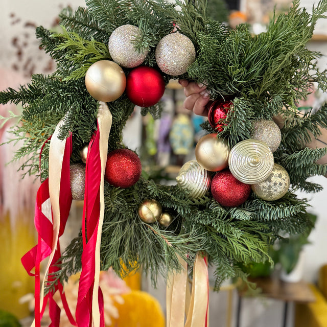 Decorative Christmas wreath with ornaments and ribbons on a blurred indoor background