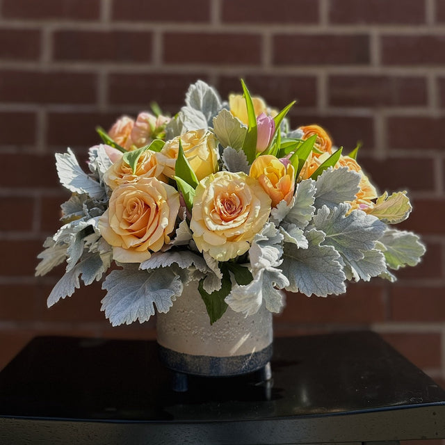 Yellow roses and ranunculuses arranged in a ceramic vase, showcasing the vibrant floral display without any additional decorations. The bouquet is elegantly presented in the vase, highlighting its cheerful and warm tones